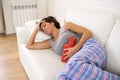 Young beautiful hispanic woman holding hot water bottle against belly suffering menstrual period pain Royalty Free Stock Photo