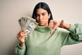 Young beautiful hispanic woman holding a pack of one dollar bunch of dollars with angry face, negative sign showing dislike with Royalty Free Stock Photo