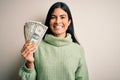 Young beautiful hispanic woman holding a pack of one dollar bunch of dollars with a happy face standing and smiling with a Royalty Free Stock Photo