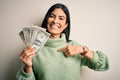 Young beautiful hispanic woman holding a pack of one dollar bunch of dollars with surprise face pointing finger to himself Royalty Free Stock Photo