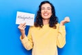 Young beautiful hispanic woman holding paper with hashtag body positive screaming proud, celebrating victory and success very