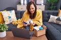 Young beautiful hispanic woman holding pills of delivery package and credit card at home Royalty Free Stock Photo