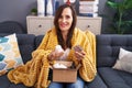 Young beautiful hispanic woman holding pills of delivery package sitting on sofa at home Royalty Free Stock Photo