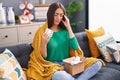 Young beautiful hispanic woman holding pills of delivery package sitting on sofa at home Royalty Free Stock Photo