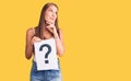 Young beautiful hispanic woman holding question mark serious face thinking about question with hand on chin, thoughtful about Royalty Free Stock Photo