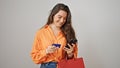 Young beautiful hispanic woman holding shopping bags using smartphone and credit card over isolated white background Royalty Free Stock Photo