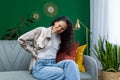 Young beautiful hispanic woman at home having severe back pain, housewife sitting on sofa in living room and massaging Royalty Free Stock Photo