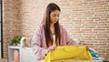 Young beautiful hispanic woman ironing clothes folding shirt at laundry room Royalty Free Stock Photo