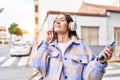 Young beautiful hispanic woman listening to music standing at street Royalty Free Stock Photo