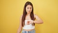 Young beautiful hispanic woman looking watch with relaxed expression over isolated yellow background Royalty Free Stock Photo