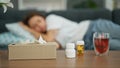 Young beautiful hispanic woman lying on the sofa sick with tissues and pills on the table at home