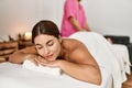 Young beautiful hispanic woman lying on table having leg massage at beauty salon Royalty Free Stock Photo