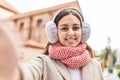 Young beautiful hispanic woman make selfie by camera wearing scarf and earmuff at street Royalty Free Stock Photo