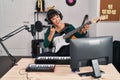 Young beautiful hispanic woman musician playing electrical guitar doing rock symbol with fingers at music studio Royalty Free Stock Photo