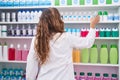 Young beautiful hispanic woman pharmacist holding bottle on shelving at pharmacy Royalty Free Stock Photo