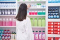 Young beautiful hispanic woman pharmacist holding product on shelving at pharmacy Royalty Free Stock Photo