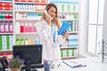 Young beautiful hispanic woman pharmacist using touchpad talking on telephone at pharmacy Royalty Free Stock Photo