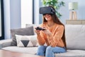 Young beautiful hispanic woman playing video game using virtual reality glasses and joystick at home Royalty Free Stock Photo