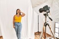 Young beautiful hispanic woman posing as model at photography studio doing ok gesture with hand smiling, eye looking through Royalty Free Stock Photo