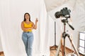 Young beautiful hispanic woman posing as model at photography studio smiling with happy face winking at the camera doing victory Royalty Free Stock Photo