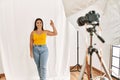 Young beautiful hispanic woman posing as model at photography studio smiling positive doing ok sign with hand and fingers Royalty Free Stock Photo