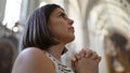 Young beautiful hispanic woman praying at Augustinian Church in Vienna