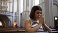 Young beautiful hispanic woman praying on a church bench at Augustinian Church in Vienna Royalty Free Stock Photo