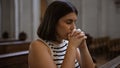 Young beautiful hispanic woman praying on a church bench at Augustinian Church in Vienna Royalty Free Stock Photo