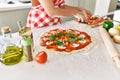 Young beautiful hispanic woman preparing italian pizza at the kitchen