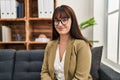 Young beautiful hispanic woman psychologist smiling confident sitting on sofa at office Royalty Free Stock Photo