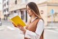 Young beautiful hispanic woman reading book at street Royalty Free Stock Photo