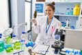 Young beautiful hispanic woman scientist holding marijuana using tweezer at laboratory Royalty Free Stock Photo