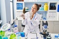 Young beautiful hispanic woman scientist holding marijuana using tweezer at laboratory