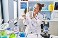 Young beautiful hispanic woman scientist holding marijuana using tweezer at laboratory