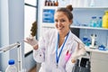 Young beautiful hispanic woman scientist holding marijuana using tweezer at laboratory