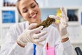 Young beautiful hispanic woman scientist smiling confident holding marijuana at laboratory