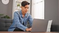 Young beautiful hispanic woman sitting on sofa using laptop to use at home Royalty Free Stock Photo