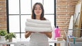 Young beautiful hispanic woman smelling clean towels at laundry room Royalty Free Stock Photo