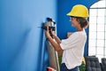 Young beautiful hispanic woman smiling confident drilling wall at new home