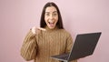 Young beautiful hispanic woman smiling confident pointing to laptop over isolated pink background Royalty Free Stock Photo