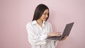 Young beautiful hispanic woman smiling confident using laptop over isolated pink background Royalty Free Stock Photo