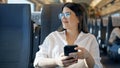 Young beautiful hispanic woman smiling using smartphone sitting inside train wagon Royalty Free Stock Photo