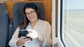 Young beautiful hispanic woman smiling using smartphone sitting inside train wagon Royalty Free Stock Photo