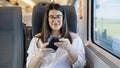 Young beautiful hispanic woman smiling using smartphone sitting inside train wagon Royalty Free Stock Photo