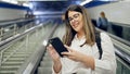 Young beautiful hispanic woman standing on escalator using smartphone in subway station of Madrid Royalty Free Stock Photo