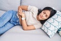 Young beautiful hispanic woman suffering for stomach ache lying on sofa at home Royalty Free Stock Photo