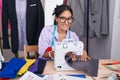 Young beautiful hispanic woman tailor smiling confident using sewing machine at tailor shop Royalty Free Stock Photo