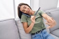 Young beautiful hispanic woman talking on the smartphone doing manicure at home Royalty Free Stock Photo