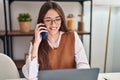 Young beautiful hispanic woman talking on smartphone using laptop at home Royalty Free Stock Photo