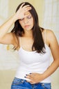 Young beautiful hispanic woman touching her belly with one hand and touching her head with her other hand, suffering Royalty Free Stock Photo